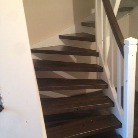Dunkle Holztreppe mit hellem Geländer und dunklem Handlauf