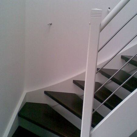 Holztreppe mit dunklen Stufen und weißem Geländer